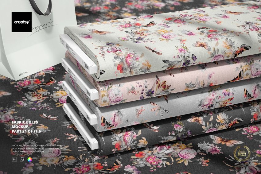 PSD mockup of fabric bolts arranged in a row, each with a unique floral print, viewed from a slightly angled perspective.