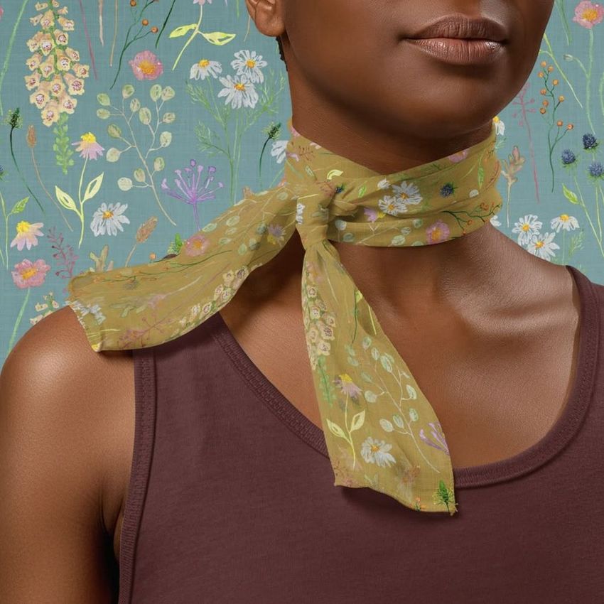 Chiffon silk neck scarf mockup tied around a woman's neck, featuring a wildflower pattern on a green background.
