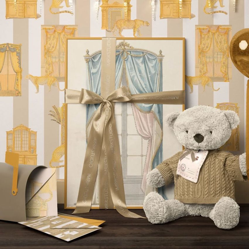 Christmas scene with a picture frame print mockup, featuring a plush teddy bear in a sweater, gold ribbon, and festive wallpaper.