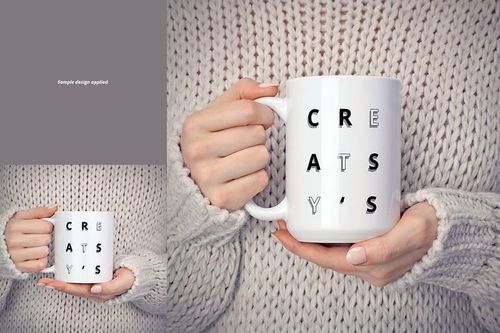White ceramic mug held in both hands, featuring bold black letters, shown against a chunky knit sweater background.