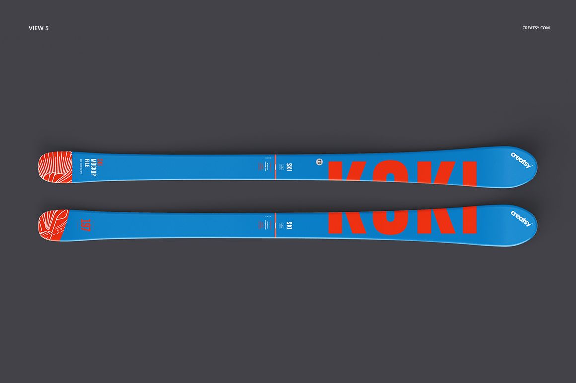Pair of blue skis with bold orange lettering and abstract orange pattern, displayed on a dark background, top view.