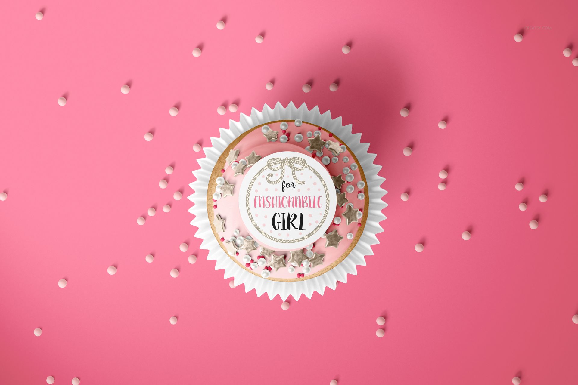 PSD mockup showing a single cupcake with a custom topper and wrap, pink backdrop and white candy sprinkles.