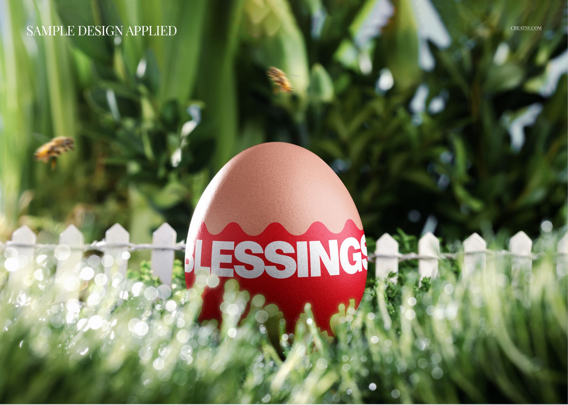 Front view of a modern Easter egg mockup with a red and pink wavy pattern and the word 'Blessings', placed on grass with a white picket fence and green foliage in the background.