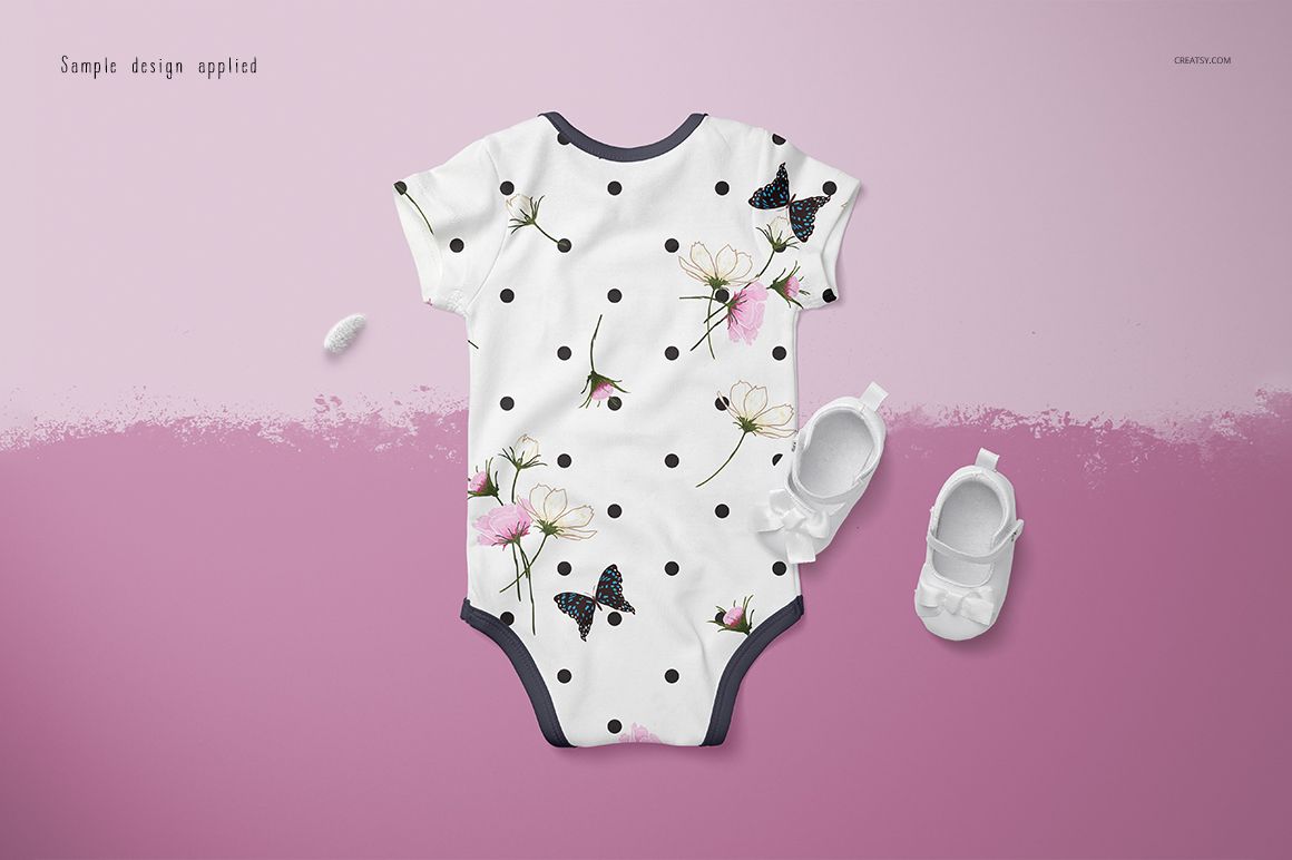 Baby onesie mockup featuring a white garment with black polka dots, floral accents, and butterfly motifs on a pink surface.