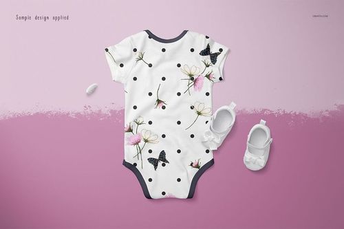 Baby onesie mockup featuring a white garment with black polka dots, floral accents, and butterfly motifs on a pink surface.