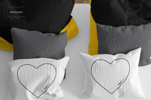 Top view of a bedding mockup set featuring two beds with black, yellow, gray, and white pillows, some with heart outlines.