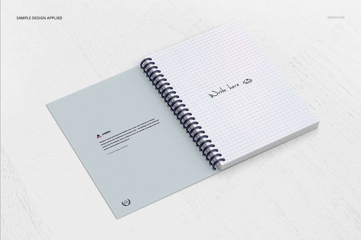 Open spiral notebook mockup with grid paper and handwritten text, displayed on a white wooden surface, top view.