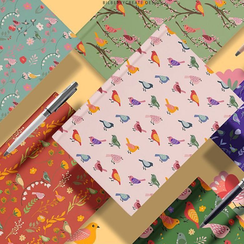 Notebook mockup featuring several notebooks with colorful bird and floral patterns arranged on a pastel yellow background.