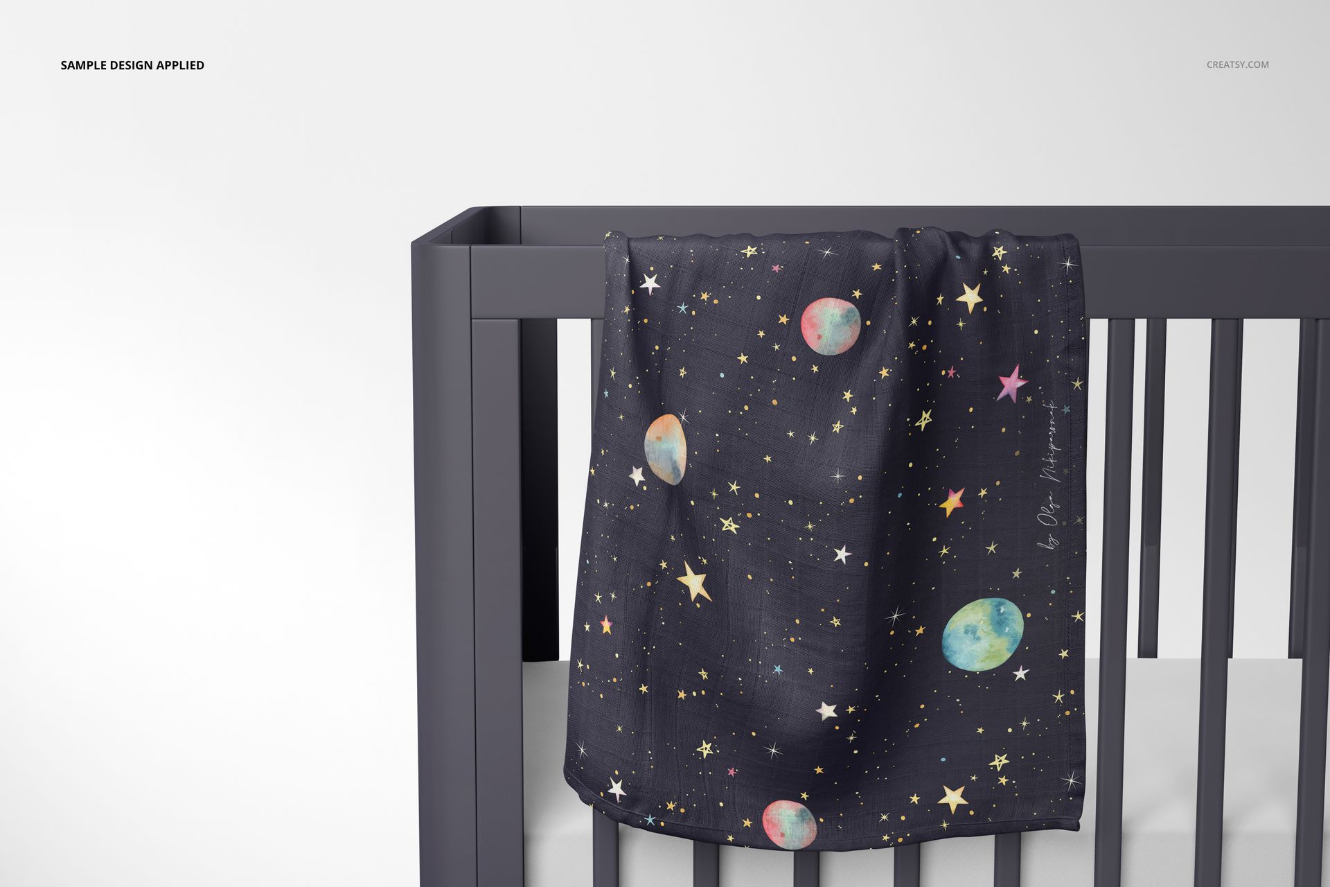 PSD mockup showing a muslin swaddle blanket with celestial motifs, displayed on the rail of a sleek gray crib.