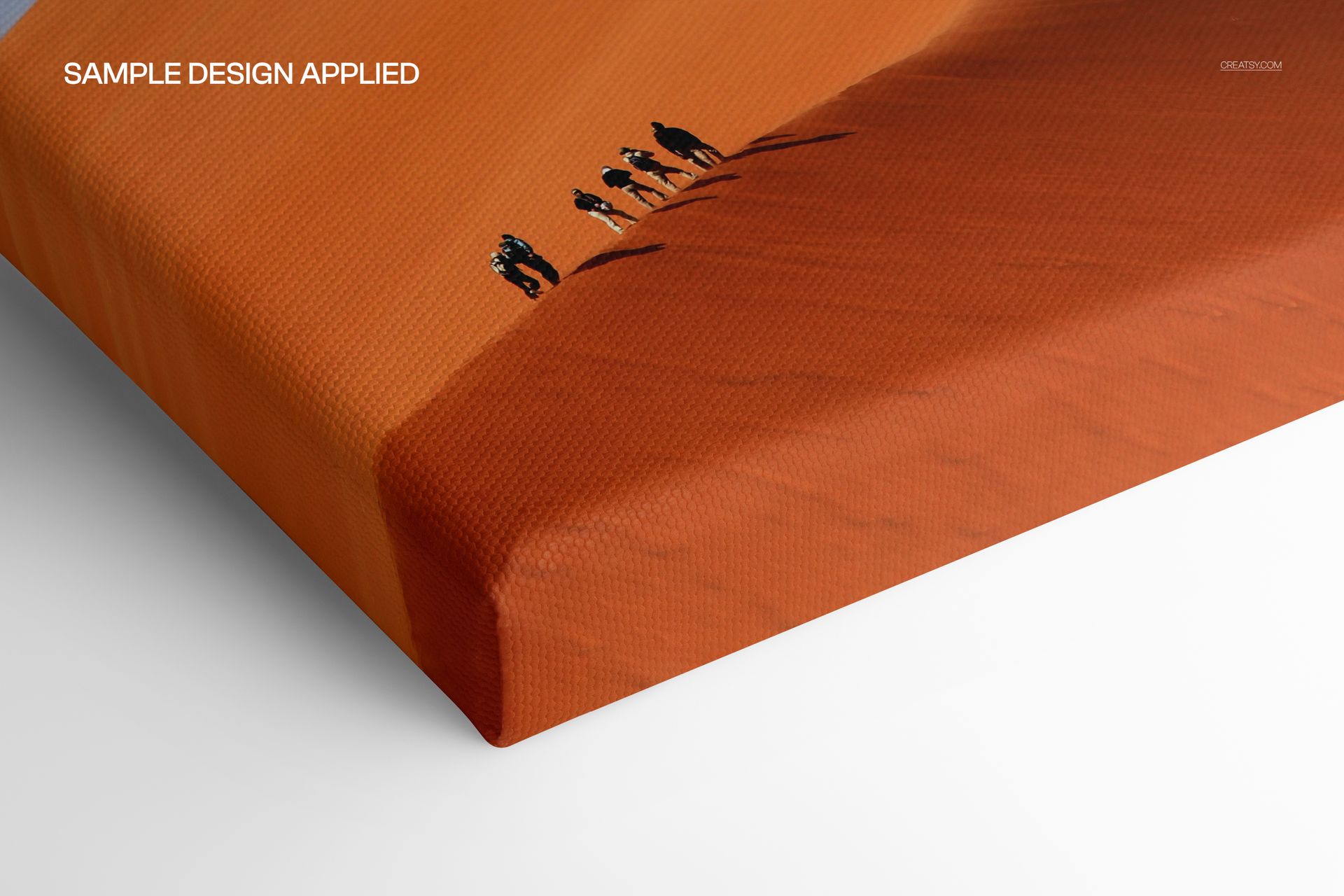 Close-up view of a cotton matte canvas print mockup with an orange desert scene and small figures on the sand.