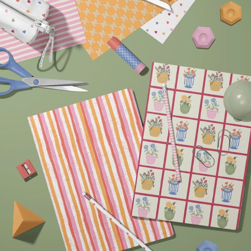 Stationery mockup featuring two A4 notebooks with colorful covers, pencils, scissors, and geometric props on a green surface.