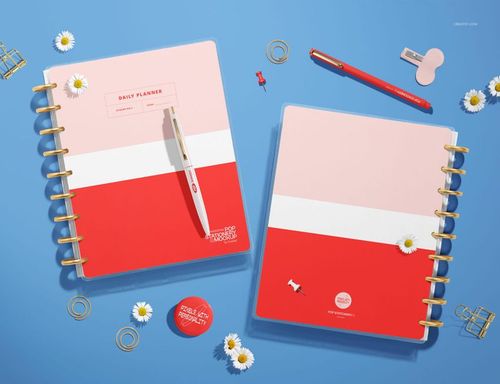 Spiral planner with dividers featuring a red, white, and pink color block design, shown from a top view on a blue surface.