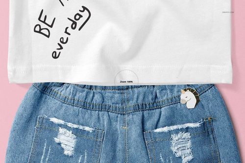 Front view of a baby tank top mockup in white with handwritten text, paired with blue denim shorts on a pink background.