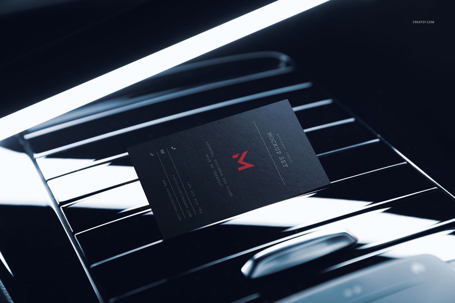 Black automotive business card mockup displayed on a car interior surface with sleek metallic lines and soft lighting.