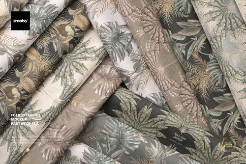 Top view of several folded fabric samples with subtle botanical prints in neutral colors, displayed in a mockup arrangement.