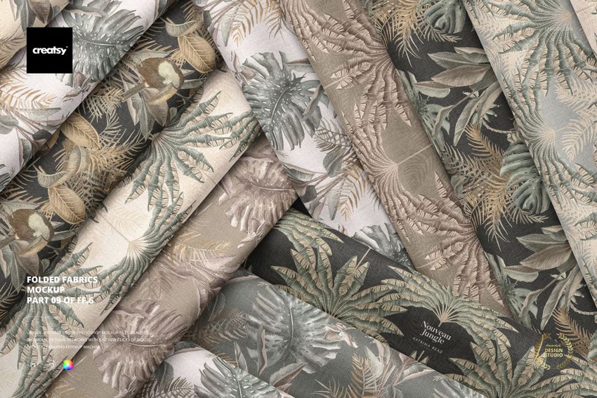 Top view of several folded fabric samples with subtle botanical prints in neutral colors, displayed in a mockup arrangement.