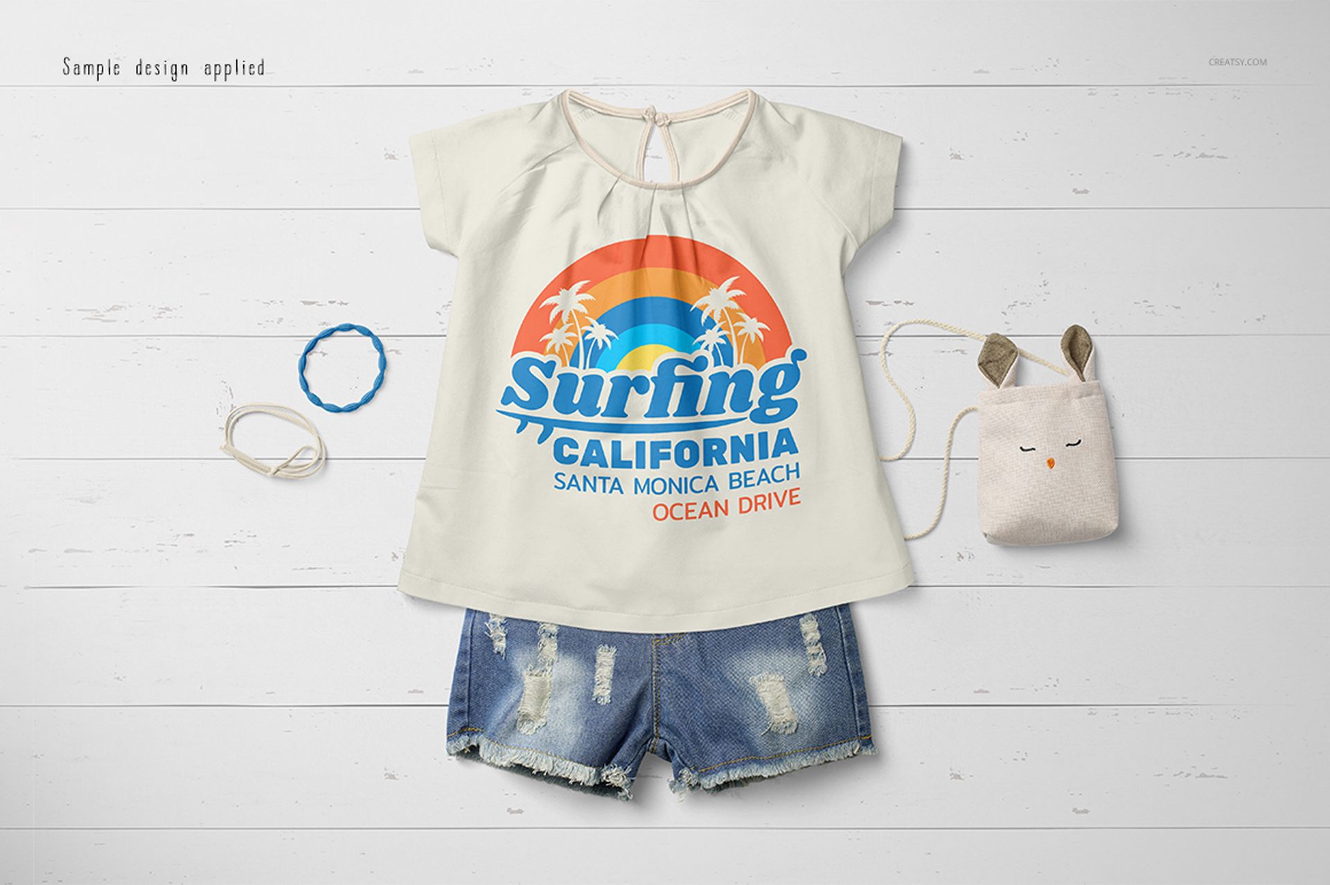 Front view of a baby summer set mockup featuring a light-colored t-shirt with a surfing graphic and denim shorts.