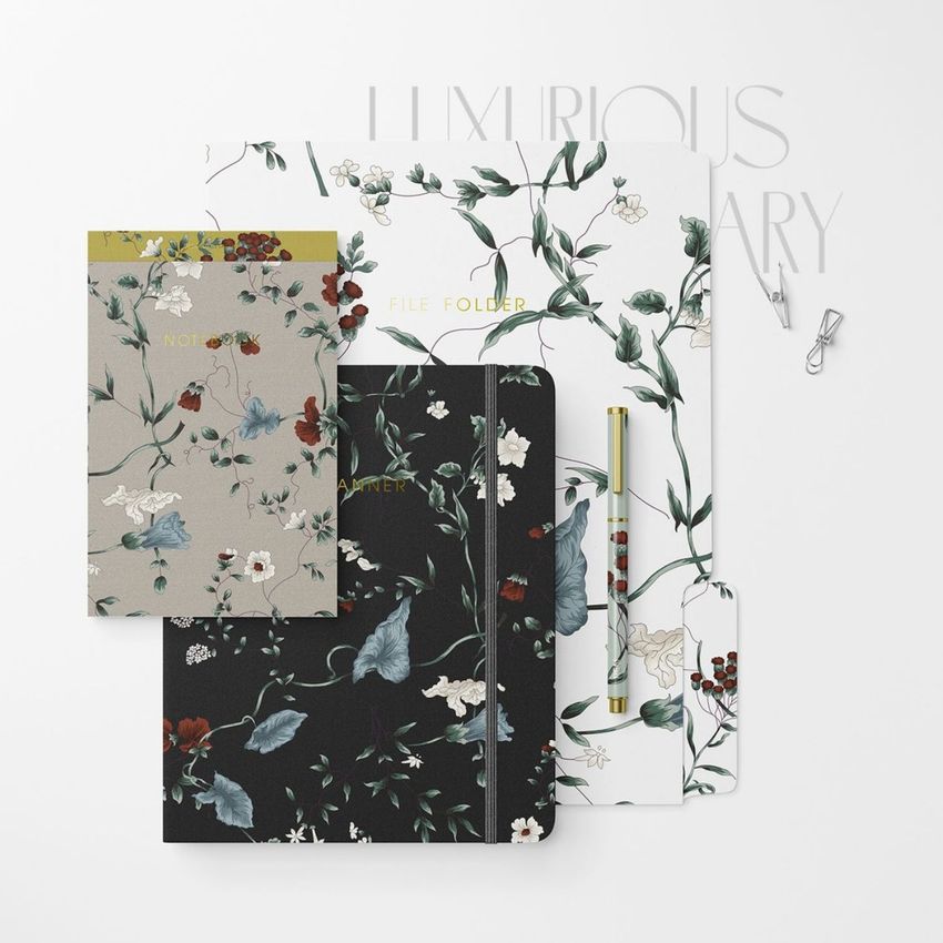 Stationery set mockup featuring a notebook, file folder, notepad, and pen with floral patterns on a white background.