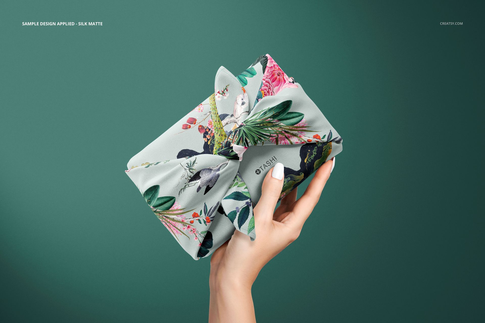 Furoshiki fabric wrap mockup featuring a tied cloth with botanical and bird motifs, shown in a front view.