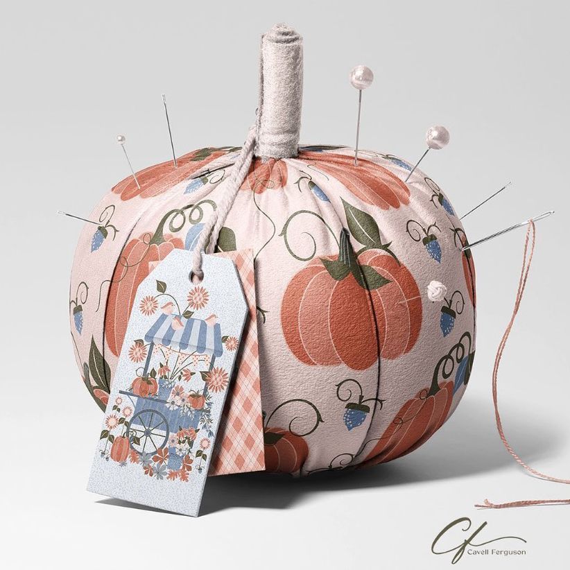 Fabric pumpkin mockup featuring a soft pink pumpkin with an illustrated pattern, used as a pincushion with pins and a decorative tag.