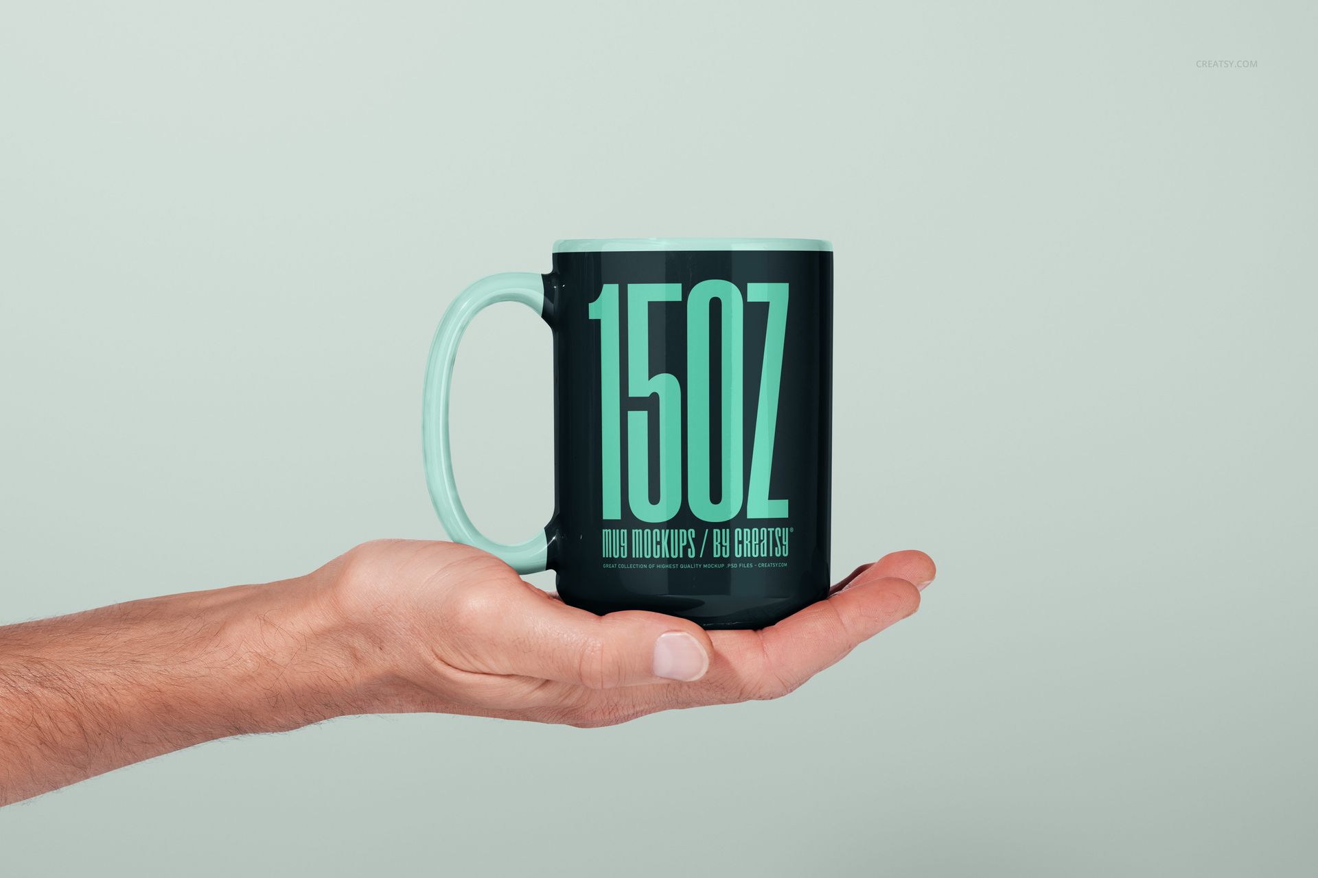 PSD mockup featuring a 15oz mug in black and mint green, shown from the side, supported by a human hand.