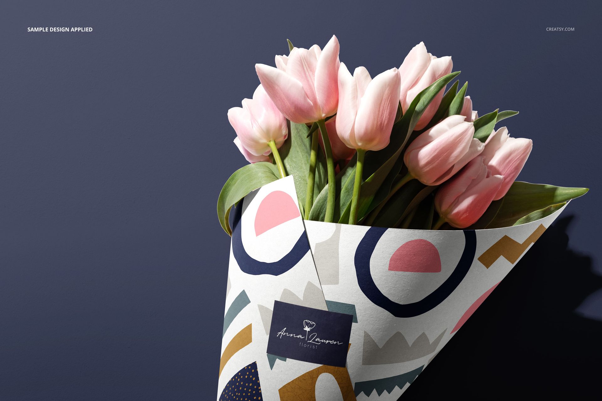 Front view of a flowers packaging cone mockup holding pink tulips, wrapped in patterned paper with abstract shapes.