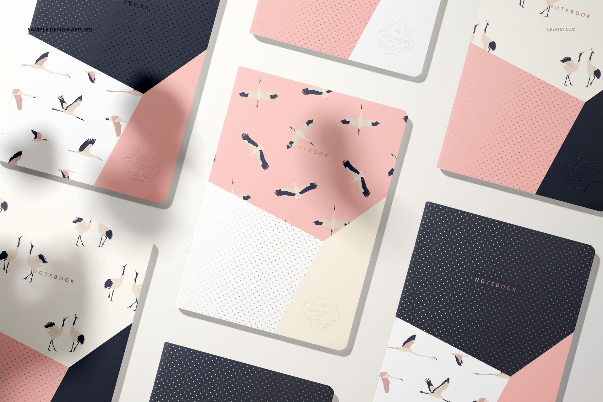 A5 notebook mockup set arranged on a light surface, featuring covers with pastel pink, white, navy, and bird patterns.