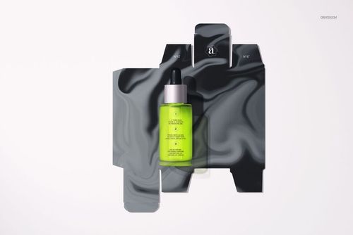 Front view of a dropper bottle with a black cap and bright green liquid, placed on a black marbled packaging mockup.