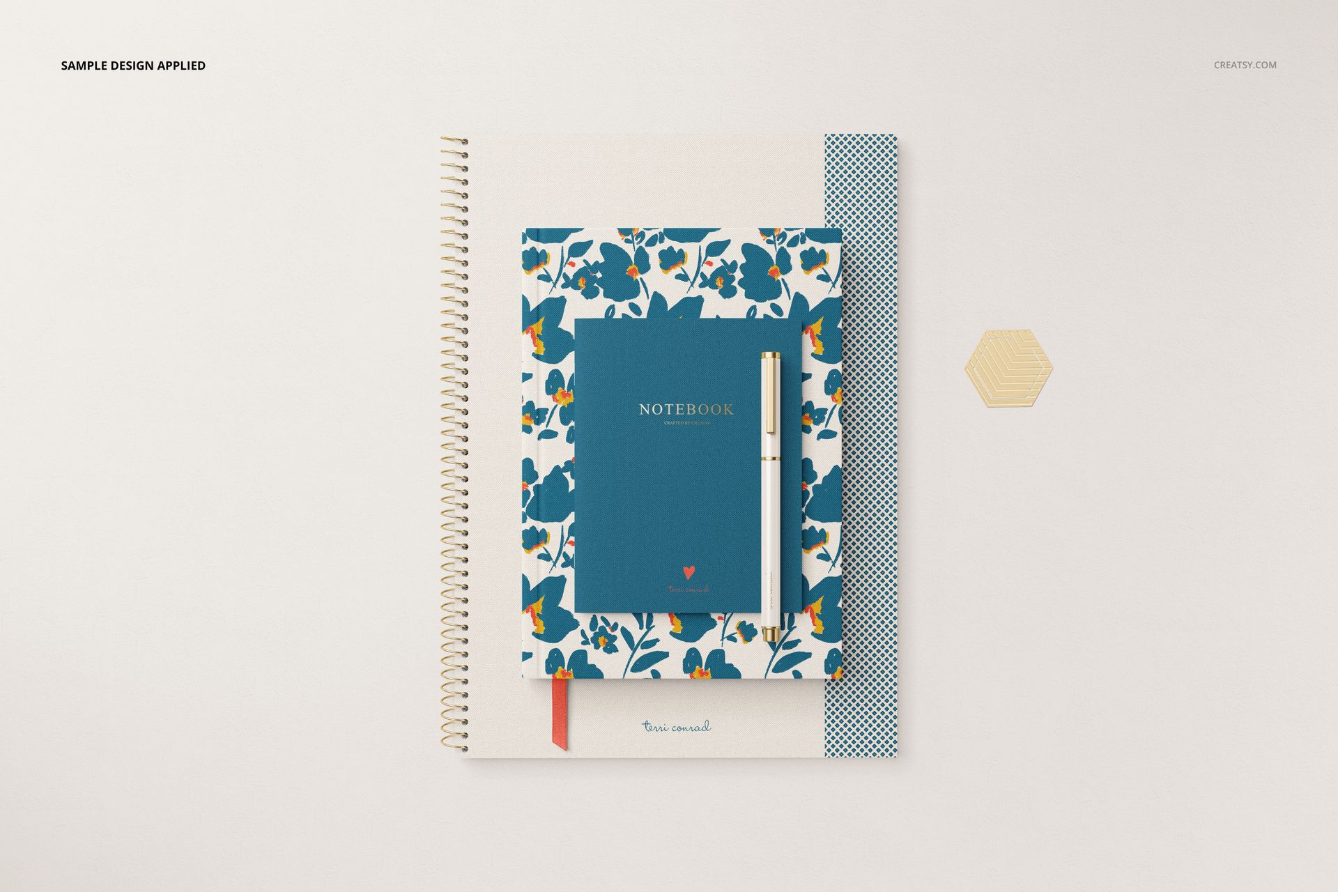 Stationery set mockup featuring a spiral notebook, a blue floral notebook, and a patterned pen on a light surface.