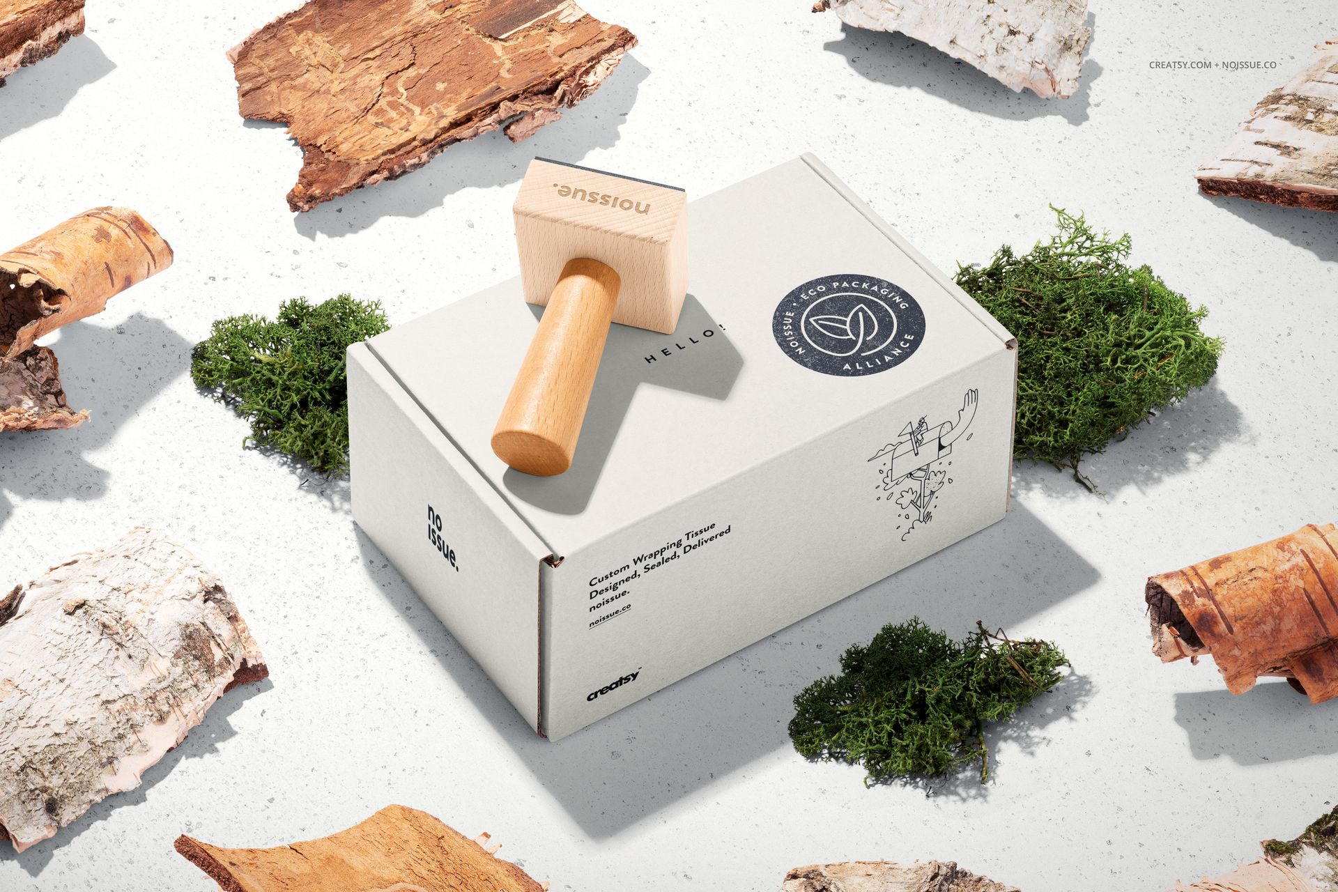 Mockup of a wooden stamp and packaging box, displayed with scattered moss and bark fragments on a textured background.