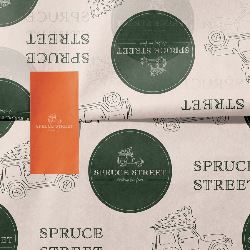 Wrapping paper mockup featuring a repeating green circular logo and text, with an orange sticker on a light background.