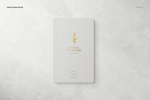 Stationery planner mockup featuring a minimalist white cover with gold accents, displayed on a marble texture.