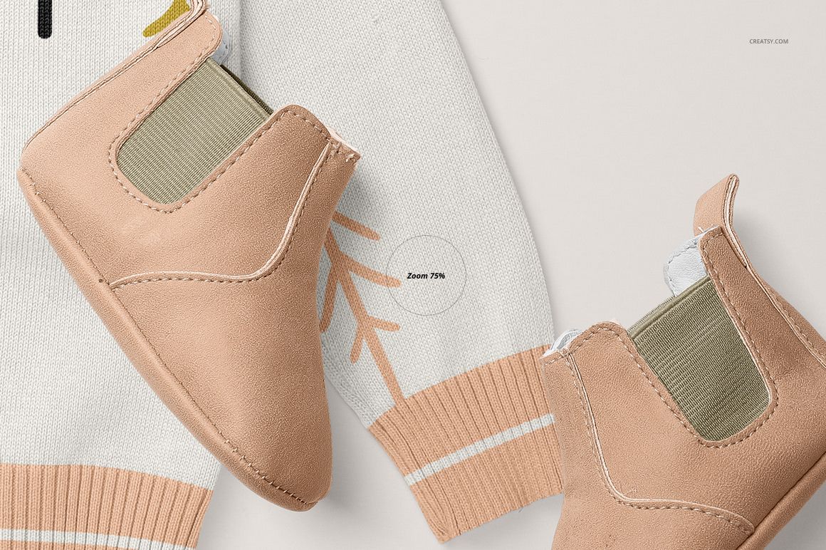 Close-up of a baby cardigan sweater mockup with light beige baby shoes placed on a white surface. The sweater features soft peach and white accents.