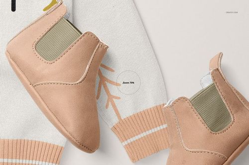 Close-up of a baby cardigan sweater mockup with light beige baby shoes placed on a white surface. The sweater features soft peach and white accents.