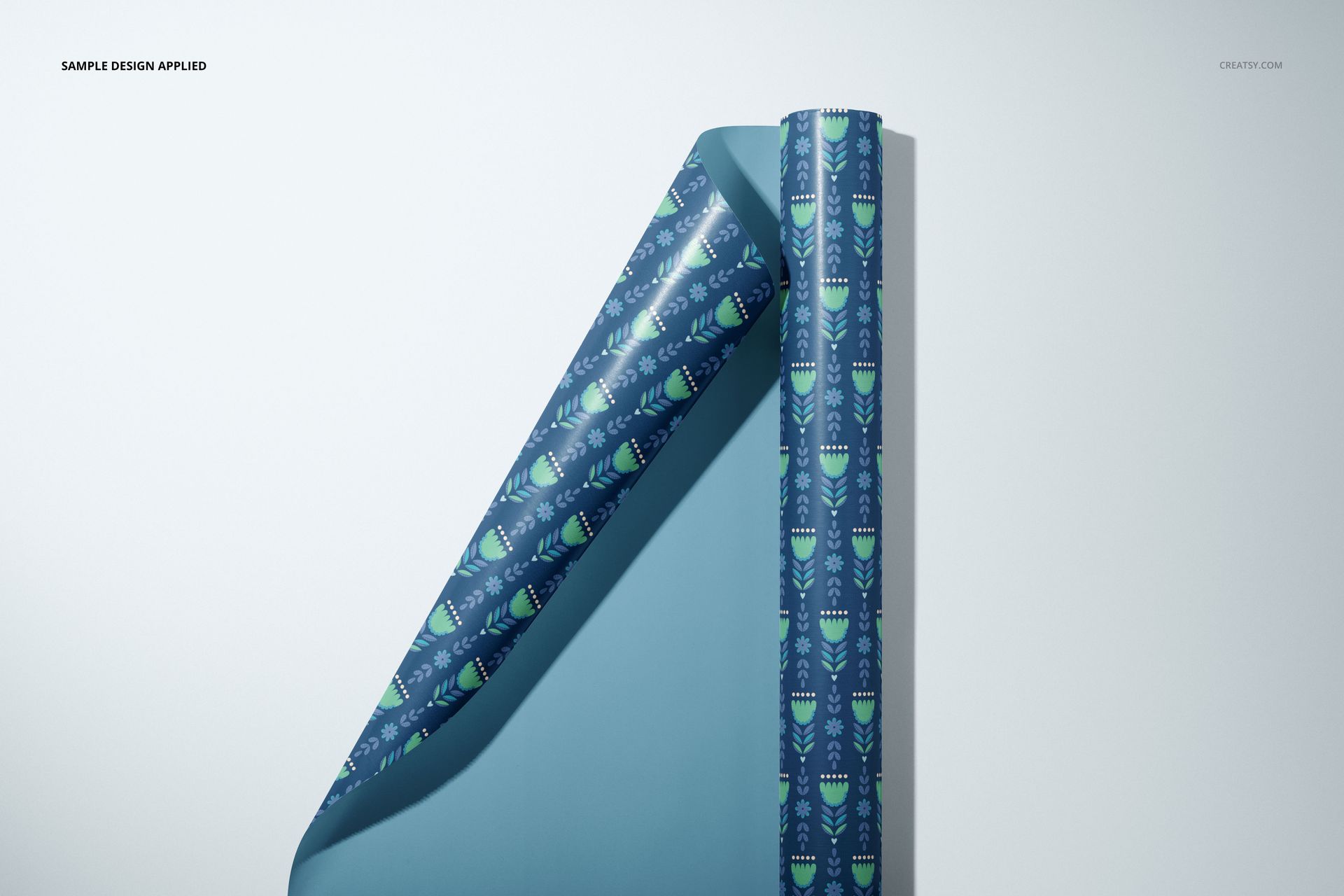 Front view of gift wrapping paper mockup with a folded edge, featuring a blue background and geometric green pattern.