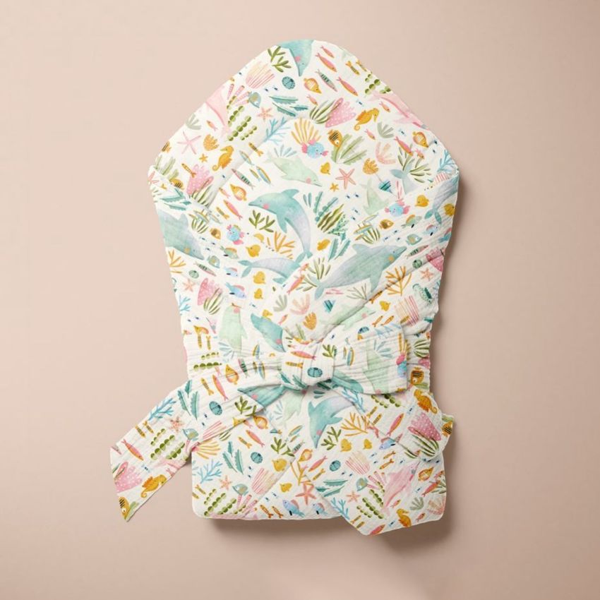 Muslin baby wrap mockup featuring a sea-themed pattern with dolphins, coral, and fish on a soft beige background.