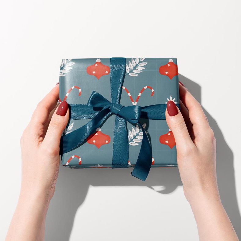 Gift box mockup featuring blue wrapping paper with festive red and white holiday motifs, tied with a dark blue ribbon.