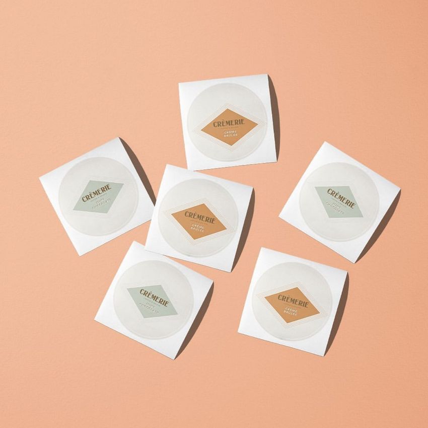 Sticker mockup showing six square sheets with round stickers arranged on a peach background, each with simple text designs.