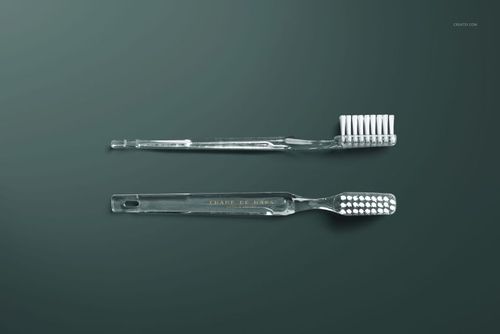 Minimalist hotel dental kit mockup featuring two clear toothbrushes, viewed from above against a green backdrop.