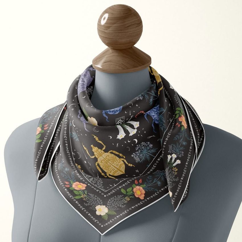 Silk scarf mockup displayed on a mannequin torso, featuring a dark background with colorful floral and insect patterns.
