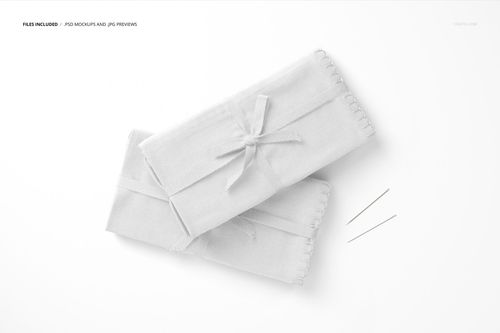 Top view of light gray folded fabrics mockup, each tied with a ribbon, placed beside two straight sewing needles.