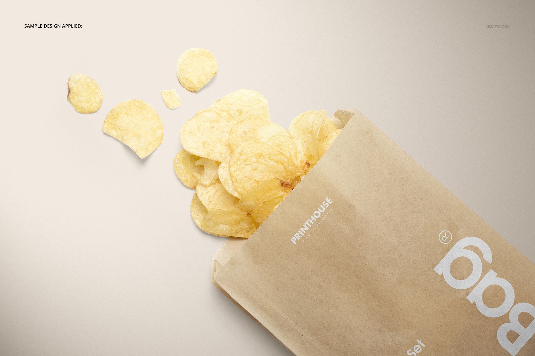 Kraft brown paper snack bag mockup with potato chips spilling out, shown from a top angled perspective on a light background.