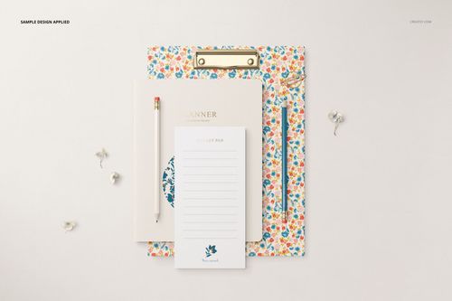 PSD mockup of a stationery bundle with a clipboard, planner, notepad, and pencil, accented by small floral props.
