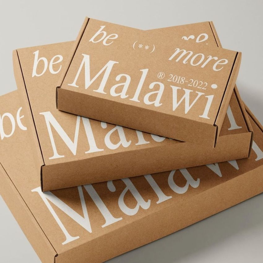 Mailing box mockup featuring three stacked kraft cardboard boxes with large white text and minimalist design on a neutral background.