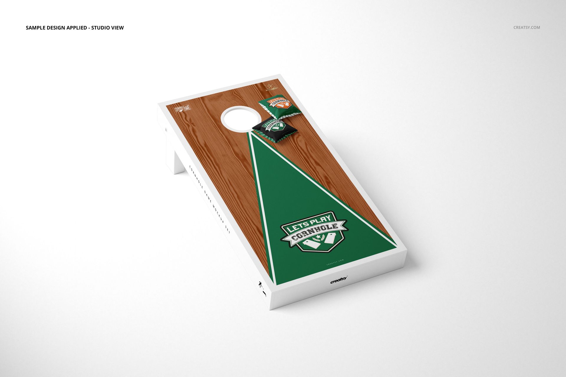 PSD mockup of a cornhole board featuring a brown wood texture and green triangle pattern, with two bean bags.