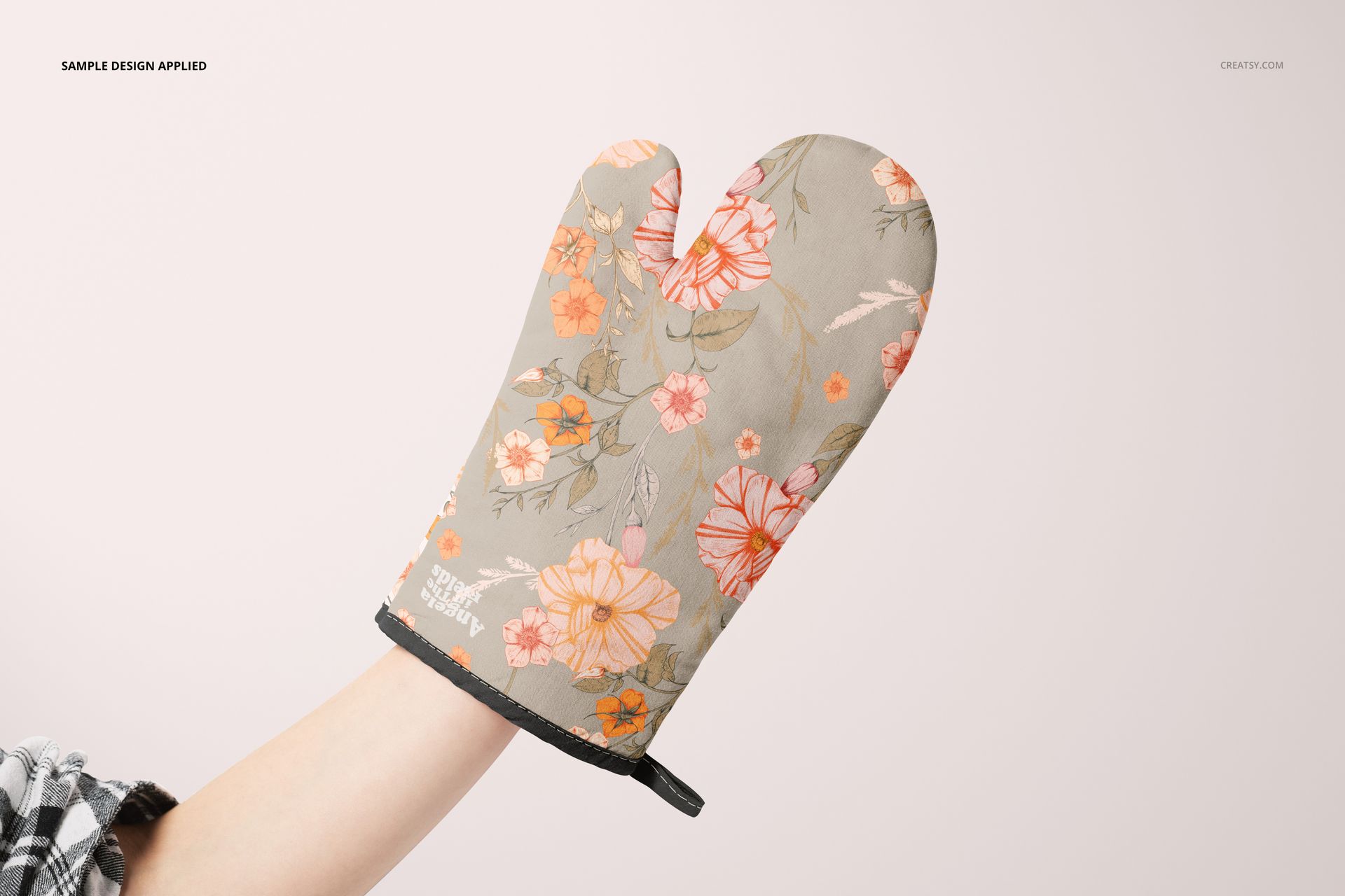 PSD mockup of a floral oven mitt featuring soft orange and pink blossoms, displayed from the front in a neutral setting.