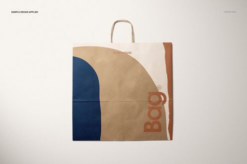 Front view of a kraft shopping paper bag mockup with abstract blue and brown design, handles visible at top.