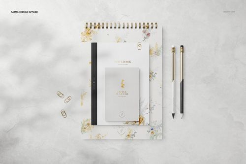 PSD mockup featuring a stationery set with floral patterned notebook, planner, pens, and paper clips arranged neatly.