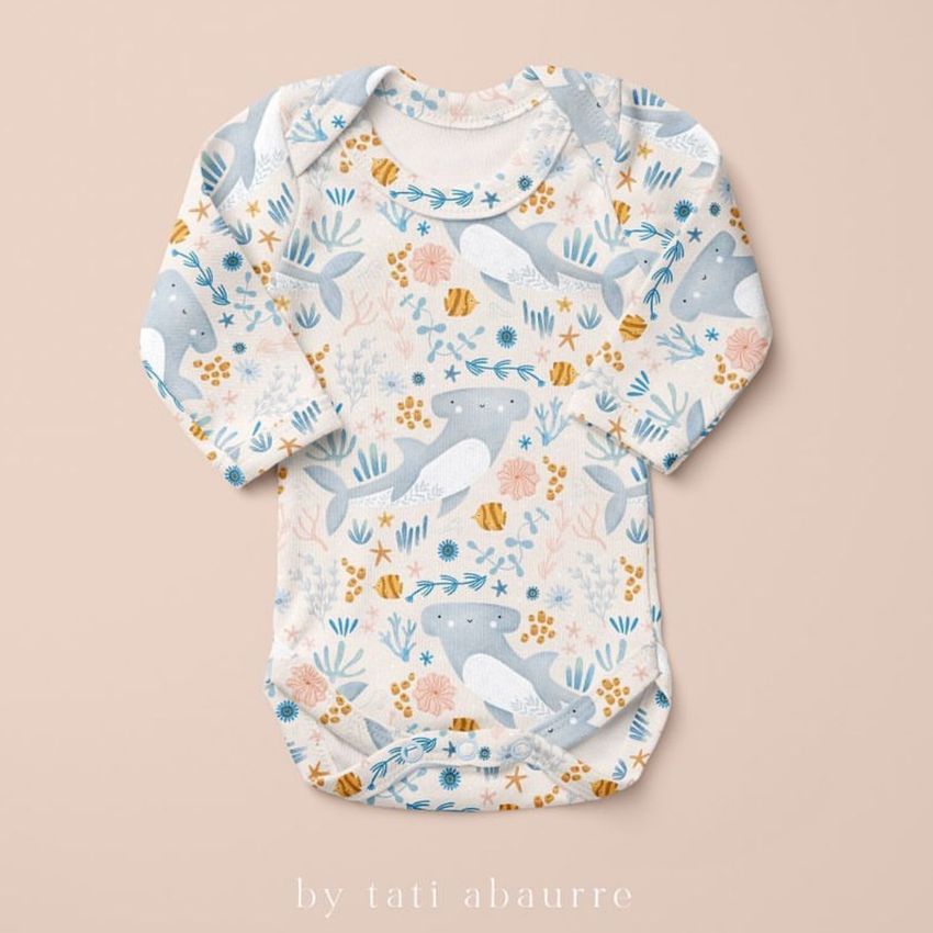 Baby long sleeve bodysuit mockup featuring a playful shark and sea life pattern in blue, gray, and orange on a beige background.