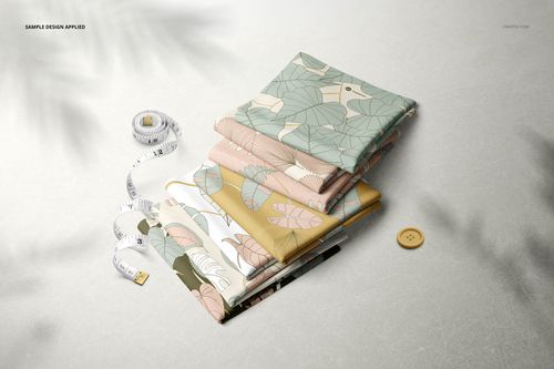 Fabric stack mockup featuring assorted folded textiles in soft colors with leaf designs, viewed from the front.